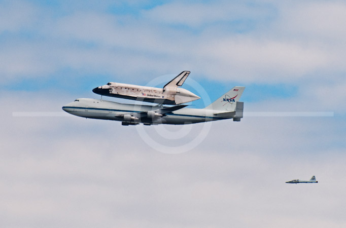 HD_STC-78 - Space Shuttle Discovery mounted on top of a a special Boeing 747 flys over Washington, D.C. on it's way to its new home at the Steven F. Udvar-Hazy Center at Dulles Airport. T-38 chase plane which accompanied Shuttle from Florida can be seen in lower right-hand corner.